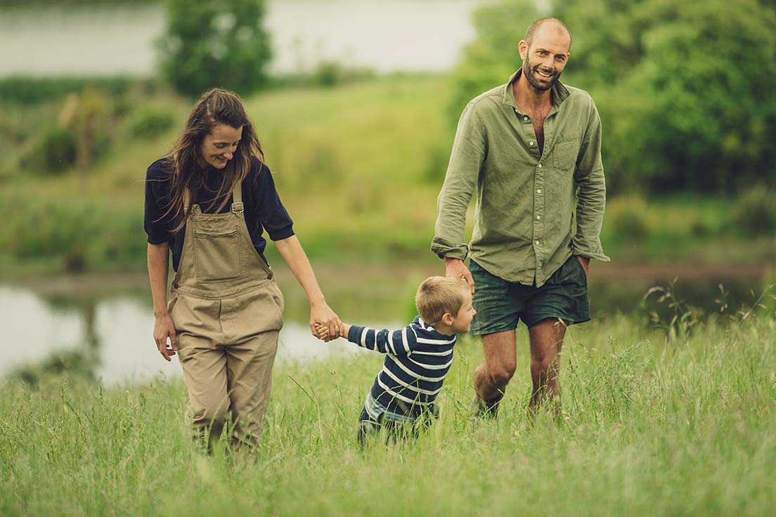 Two adults holding hands with child in field